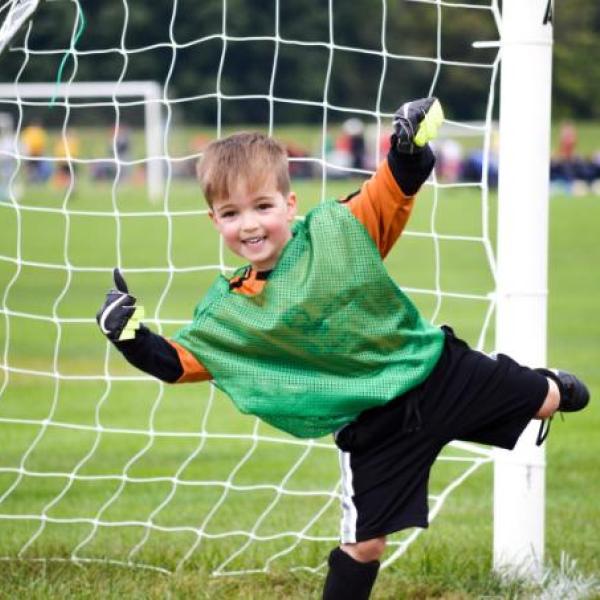 Young boy in goal of football net smiling