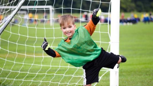 Young boy in goal of football net smiling
