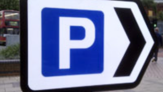 White parking sign with blue square with white P inside and black arrow pointing to right