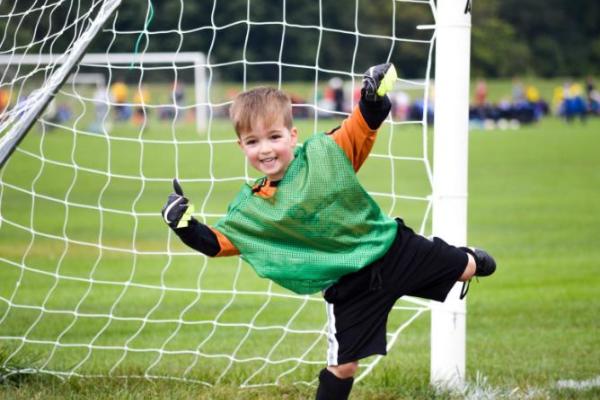 Young boy in goal of football net smiling