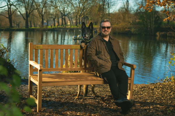 Ricky Gervais with dog on a bench of hope