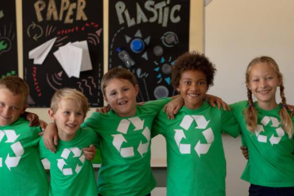 [A group of children wearing green t-shirts with the recycling logo on them]