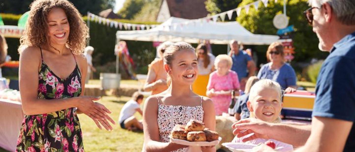 Children serving cake on a stall at a community picnic