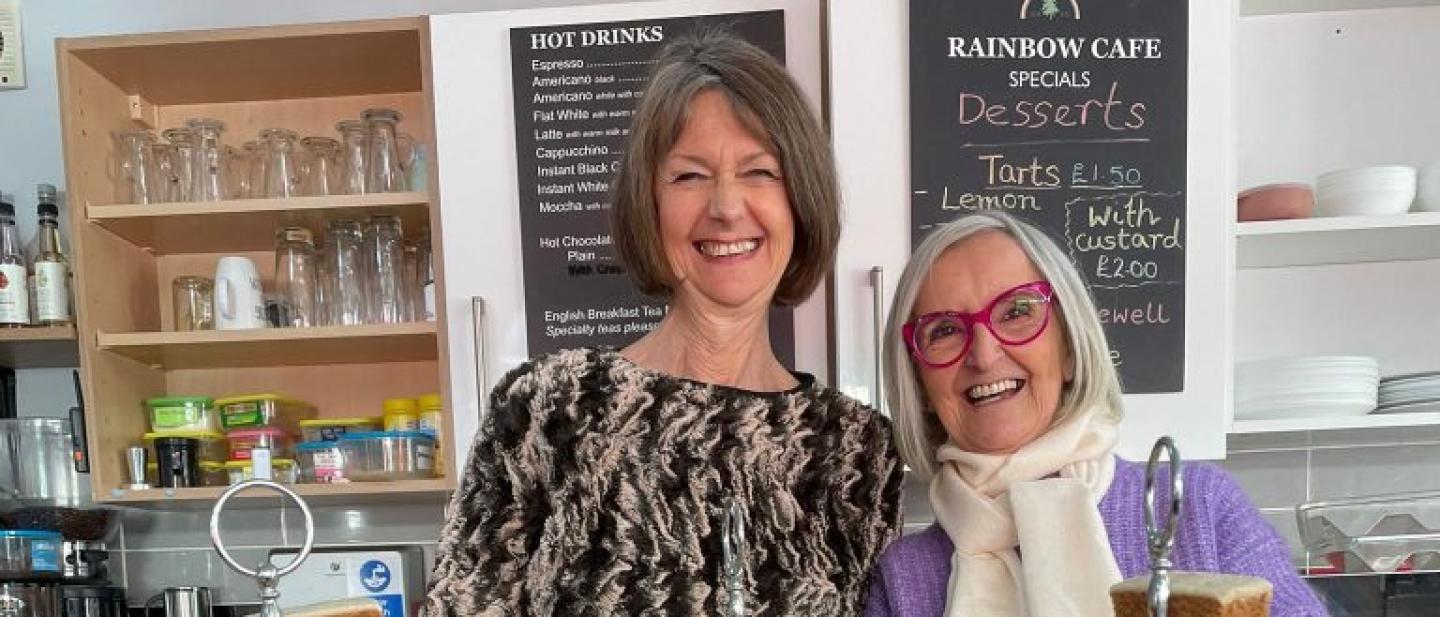 Two women behind the counter at The Rainbow Cafe with afternoon tea
