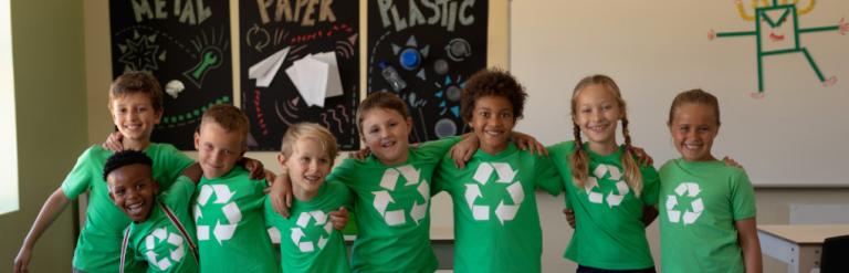 [A group of children wearing green t-shirts with the recycling logo on them]