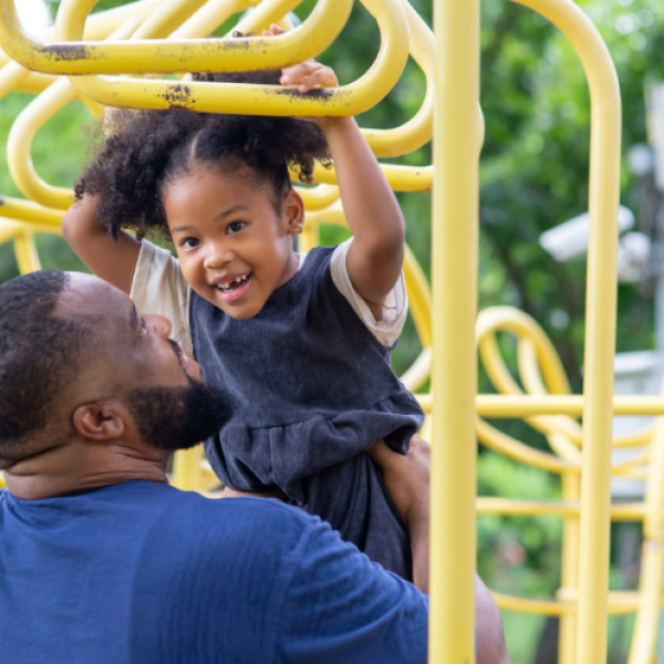 A father and daughter playing at a playground.