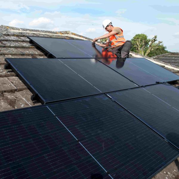 person fitting solar panels on roof of house