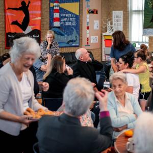 Group of people sitting around tables at the church enjoying food and drinks.