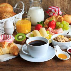 Table with coffee, croissants, fruit, bread and cereal laid out on it.