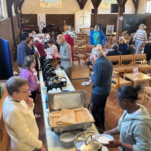 people serving breakfast at the breakfast church event with attendees chatting and eating their breakfast