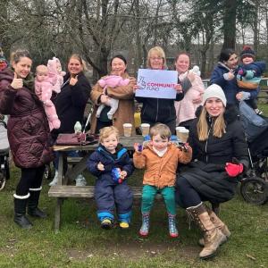 group of parents and their children sat around picnic benches at Frimley Lodge Park